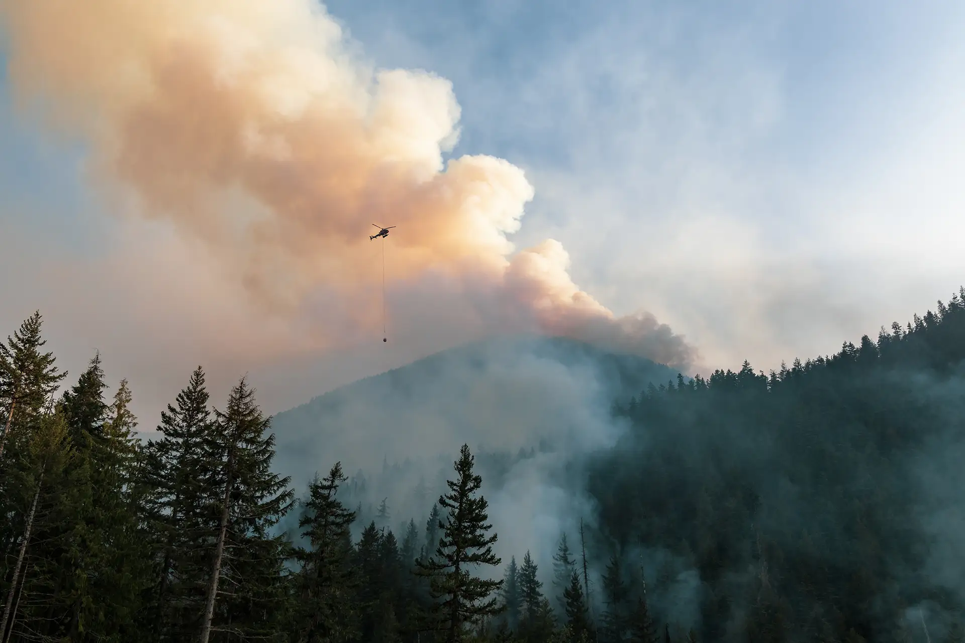 Helicopter flying over pacific northwest forest wildfire